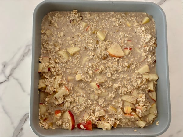 pouring ingredients in baking pan for Apple Cinnamon Oatmeal Bake pouring ingredients in baking pan